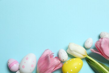 Colorful eggs with tulip flowers on pastel blue backdrop, space for your text or advertisement