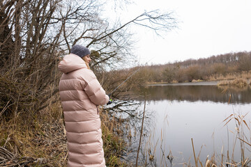 Woman fishing on the river. Fly fisherman catches fish in the morning