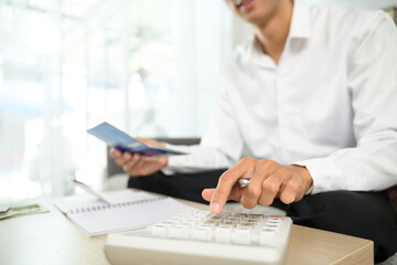Close up of man using a calculator to manage expenses. Budgeting and financial planning concept