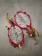 Sliced dragon fruit exposing bright white pulp, dotted with dark seeds against neutral background...