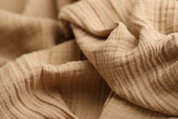 Texture of crumpled linen fabric under natural light in peach fuzz color
