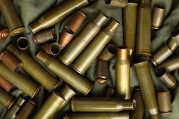 Many used rifle cartridges on military camo green fabric background
