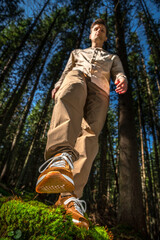 Young athletic man taking a step in the forest, shot from below with a focus on his sneaker.
