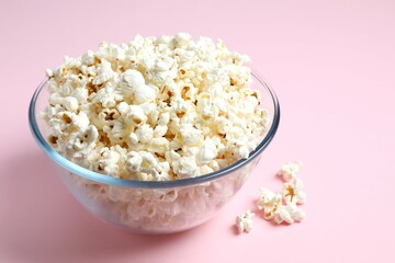 Delicious popcorn in a bowl on a colored background