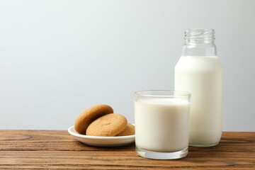 Glass and bottle of milk with cookies on table