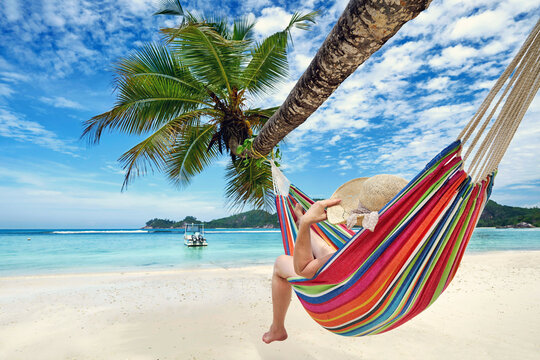 recreation on Seychelles island, relaxed woman in a colorful hammock on the beach - Powered by Adobe