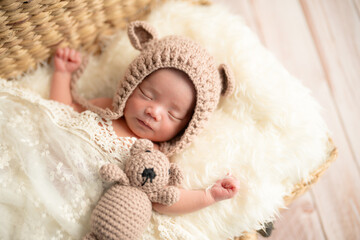 ニューボーンフォト_おくるみに包まれて幸せそうに新生児微笑を見せてすやすや眠る生まれたての赤ちゃん
