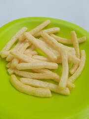 French fries on a green plate. French fries with a slightly long and sometimes curved shape are called 