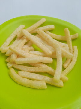 French fries on a green plate. French fries with a slightly long and sometimes curved shape are called "shoe string." made from potato pieces fried in hot cooking oil. isolated white background