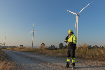 Survey Team Alternative energy for future. Engineers survey and checking wind turbines in sunset....