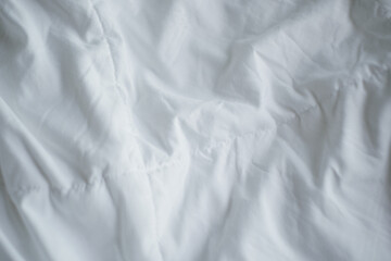 Closeup of beautiful white shiny crumpled  fabric sheets on the bed