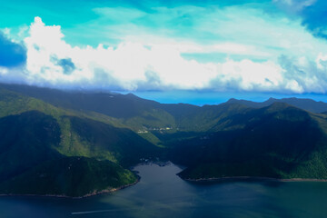 Looking through airplane window with the view of cloudscape. Fluffy white clouds with blue sky over the mountains in Hong Kong. Hong Kong rural area, Mountains from the high angle view. Nature scene.