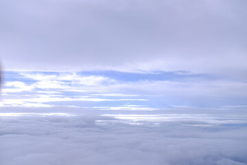 Looking through airplane window with dramatic cloudscape. white clouds with the blue sky from the high angle view. Cloudscape background. Nature scene.
