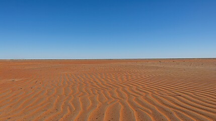 Naklejka premium A vast desert landscape with rippled sand under a clear blue sky, showcasing the beauty of arid environments.