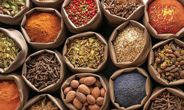 Turkish A variety of spices are displayed in bags, including cinnamon, cumin, and turmeric. The bags are arranged in a row, with some bags overlapping each other. The spices are colorful and fragrant