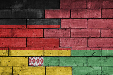 colourful painted big flag of germany and flag of belarus on a massive old brick wall background....