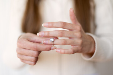 Woman Wearing Diamond Engagement Ring. Close-up of a woman putting on a diamond engagement ring,...