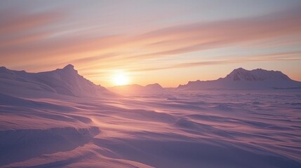 The glowing sunset bathes a vast snow-covered terrain in soft hues of pink and orange, highlighting the silhouette of rugged mountains under a tranquil sky