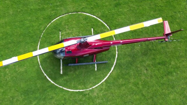 unique perspective red helicopter parked grass field heliport essence aviation operations london top down birdseye aerial shot view downward helipad scenic travel 