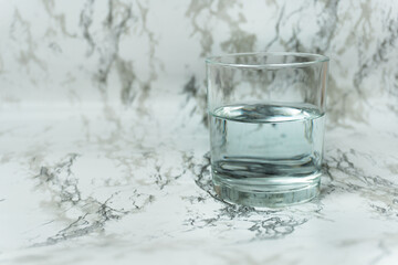 Tap water in glass on marble clean white background. Purity, rebirth, nature, healthy lifestyle, drinking more