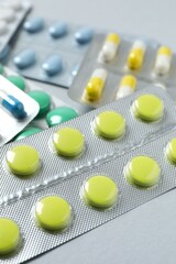 Pills in blister packs on gray background, close up