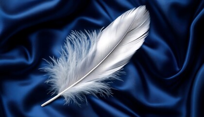 Fototapeta premium Elegant White Feather on Smooth Luxurious Navy Silk Fabric Background for Textile and Home Decor Inspirations. Floating feathered quill pen writing poetic verses on a canvas of midnight blue velvet,