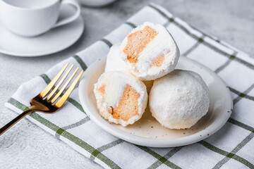 Coconut ice cream balls on white plate with cutlery