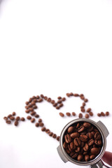 A coffee portafilter filled with roasted beans is held in the foreground with a heart shape created from coffee beans in the background on a clean white surface, representing a passion for coffee and