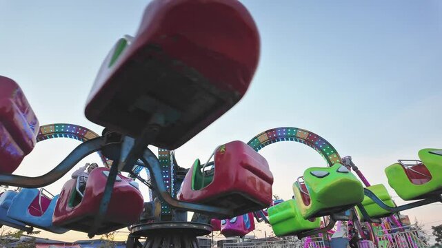 Colorful amusement park ride with vibrant lights and spinning seats offers thrilling entertainment at funfair, creating unforgettable evening attraction filled with joy.