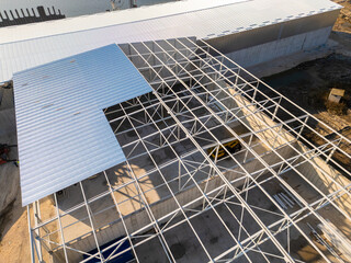A construction site with a partially built warehouse featuring a steel framework and metal roof....