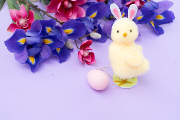 Easter scene with chiken in funny rabbit's ears, flowers in background.