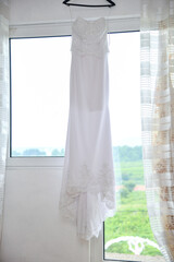 White wedding dress with a lace corset on the finger, photographed in front of a window with a strong counter light