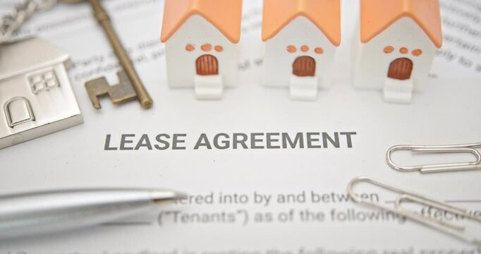 Key elements of a lease agreement and property management. House models, a key, and a pen on a lease agreement, depicting the critical steps and details involved in property leasing, legal agreements.