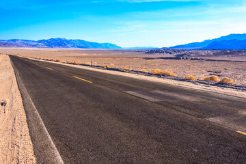 A long, empty road stretches across a desert landscape