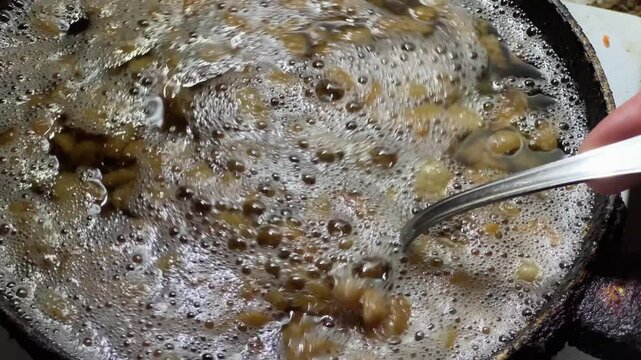 Duck fat rendering on frying pan, stirring it with spoon