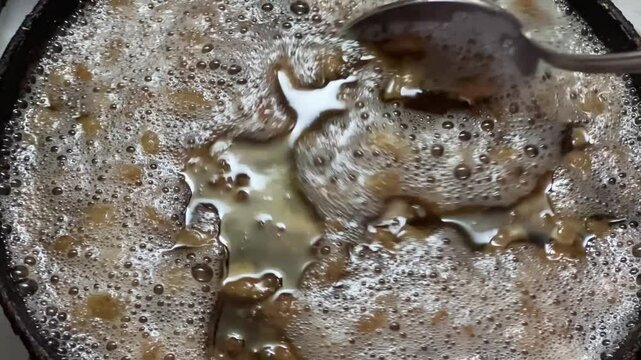 Duck fat rendering on frying pan, stirring it with spoon