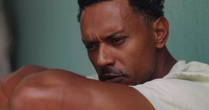 Man of African descent leaning on arms with focused and thoughtful expression, introspective and reflective moment, mental health awareness, inner thoughts