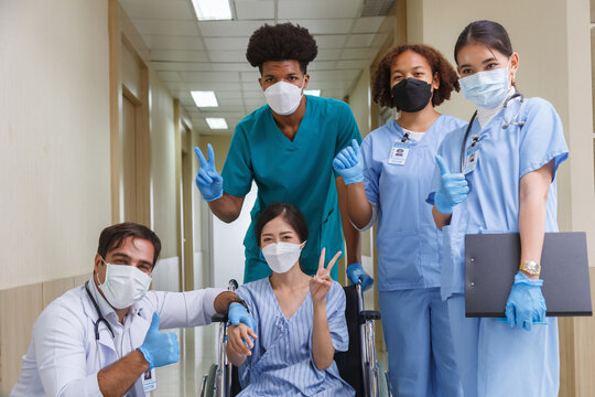 doctor and medical students team examining a patient in a wheelchair during a hospital consultation. Healthcare professionals wearing face masks and gloves for infection control.