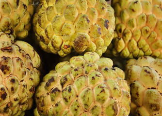 sugar pineapple on shop display. sweetsop or Pile of custard apple, Exotic tropical plant, asian fruit. Cherimoya sweet fruits. Annona Background. Sugar apple fruit. Heap of stacked custard apple.
