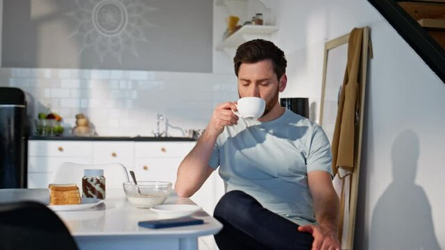 Pensive man drinking tea at morning kitchen closeup. Guy sipping hot beverage