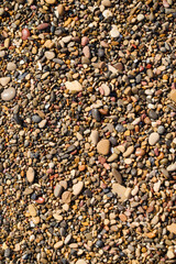 Colorful collection of pebbles and stones on sunlit ground at a beach
