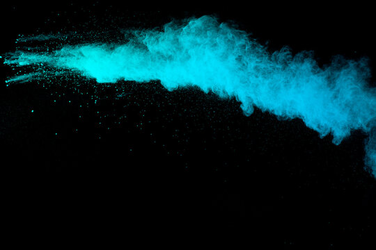 Abstract green blue powder explosion on black background. Blue dust on dark