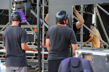 Technicians working on stage assembling giant LED screen panels for rock event. Men working on...