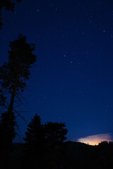 Naklejka premium Starry Night Sky Over Mountain Landscape with Glowing Horizon and Snow-Capped Peaks
