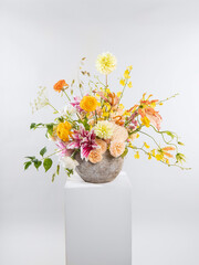 Colorful spring floral arrangement with yellow dahlias, orange ranunculus, pink lilies, and delicate greenery, ideal for Valentine’s and Women’s Day