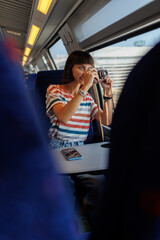 A young girl uses a camera to photograph a beautiful view from the window while traveling by train....