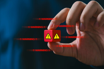 Hand holding a red cube with warning symbols, signifying caution in digital security and data...