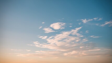 A serene sky with gentle clouds at sunset, creating a tranquil atmosphere and a blend of warm and cool colors.