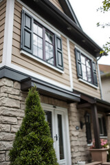 Fototapeta premium Modern House Exterior with Stone and Brick Facade, featuring Shuttered Windows and Landscaping