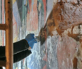 Restorer paintings on frescoes of religious motifs in Orthodox Christian monasteries	